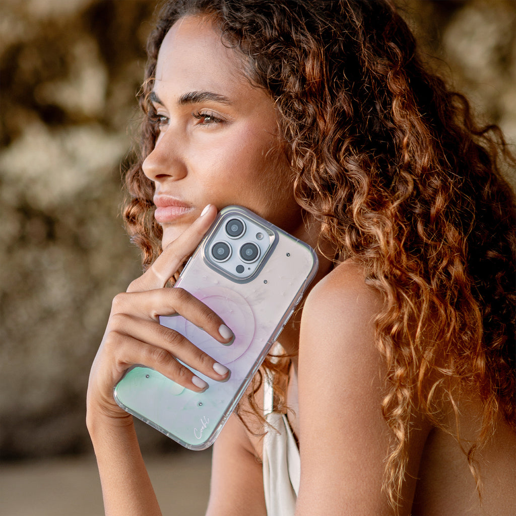 A model holding CELEST iPhone 16 Pro case available in iridescent color close to her.